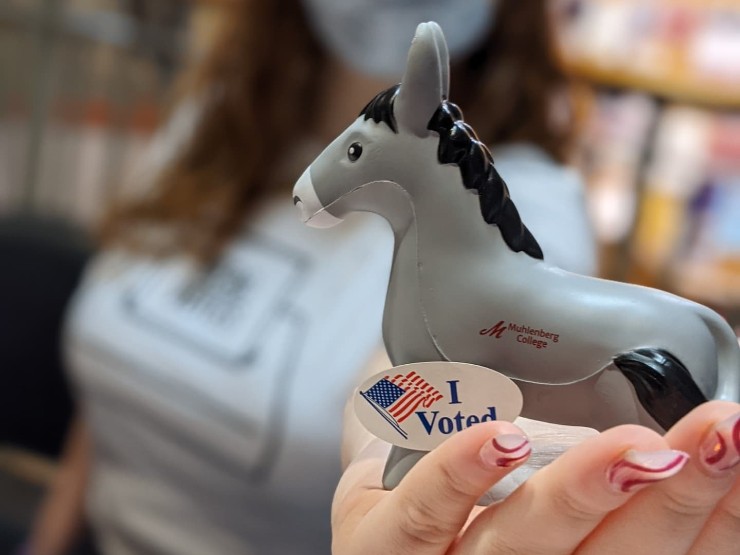 A college student holds out a plastic mule toy with an 